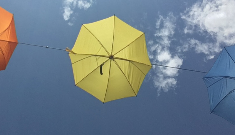 drie gekleurde parasols tegen een blauwe lucht
